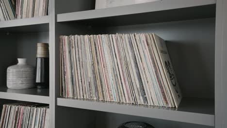 old vinyl records on the shelf inside of a home