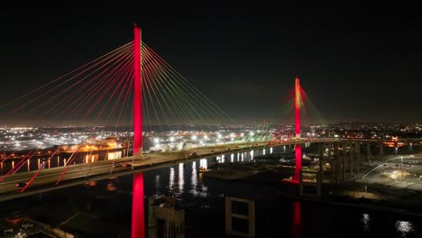 luces coloridas iluminan el puente internacional de long beach con la ciudad en el fondo - noche aérea