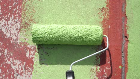 POV-First-Person-View-shot-of-a-person-painting-with-a-roller-on-a-park-floor-with-green-paint