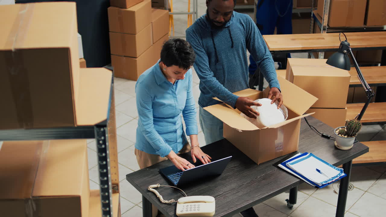 People working in a warehouse with boxes and a laptop