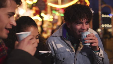 group of friends drinking mulled wine at christmas market