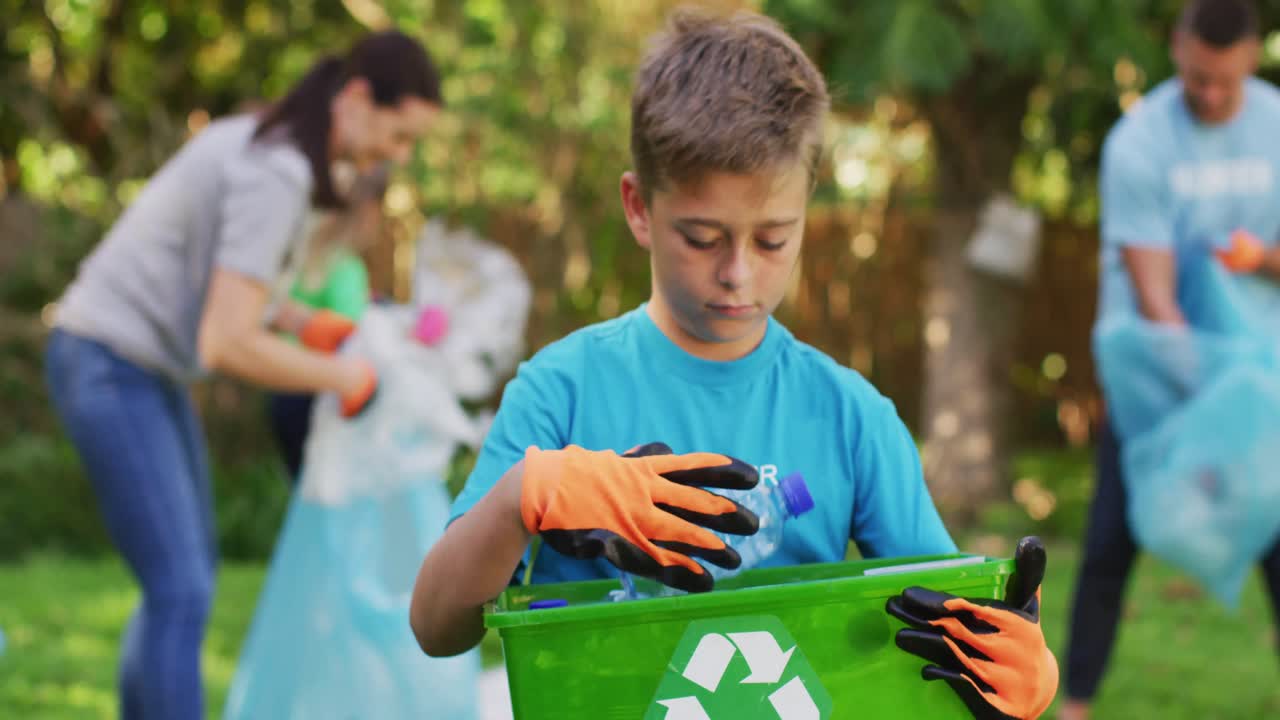 hijo caucásico sonriente al aire libre sosteniendo una caja de reciclaje, recolectando residuos plásticos con los padres