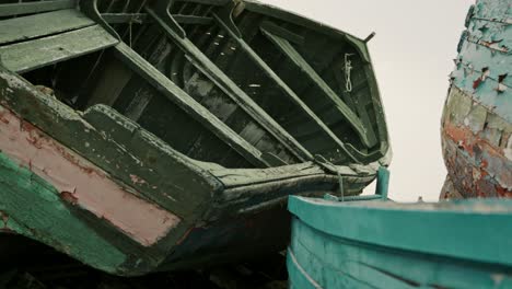 slow revealing shot of small weathered boats left to ruin in the docks