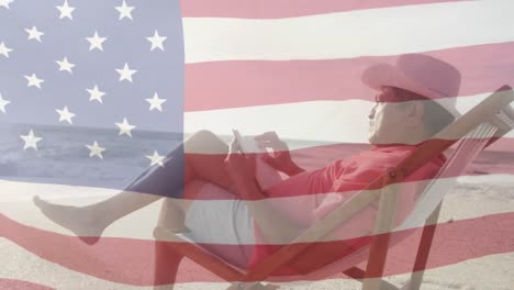 Animation-of-flag-of-united-states-of-america-over-senior-biracial-man-using-smartphone-on-beach