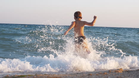 child enjoying vacation on the coast and running into sea to swim