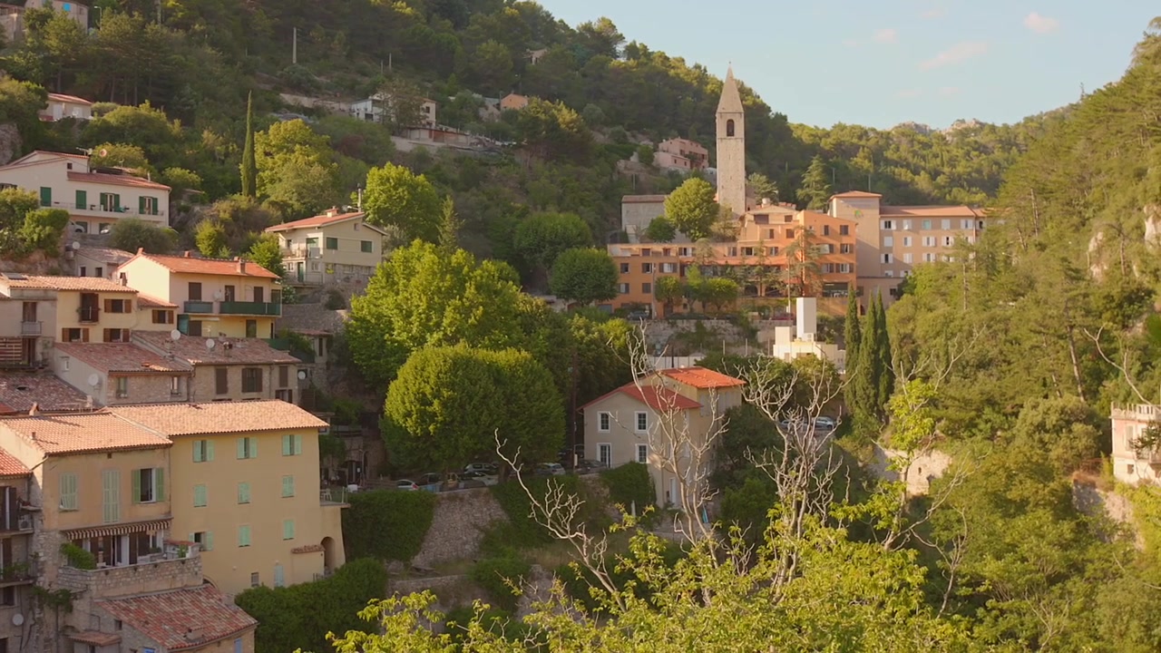 Case medievali in pietra e torre della chiesa immerse nelle rigogliose colline del villaggio di Peille, Francia