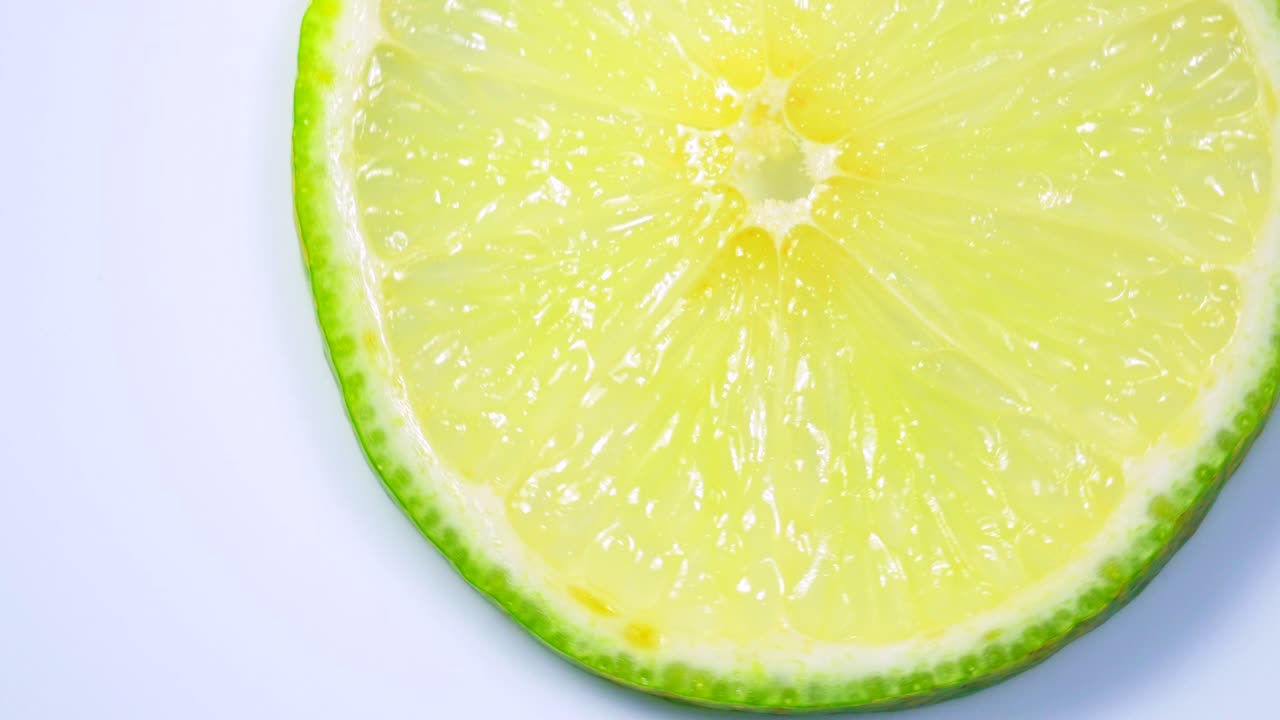 una rebanada de limón verde está girando lentamente en el estudio con los detalles.