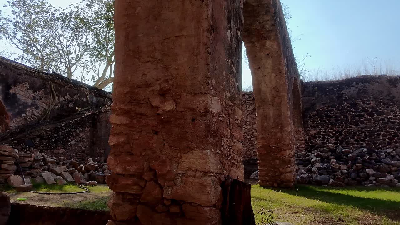 Ruins of Ex Hacienda San Jacinto Ixtoluca, slow pan left. La Mezquitera, Morelos. Crumbling stone arches and walls of a colonial-era hacienda surrounded by green grass and sunlight.