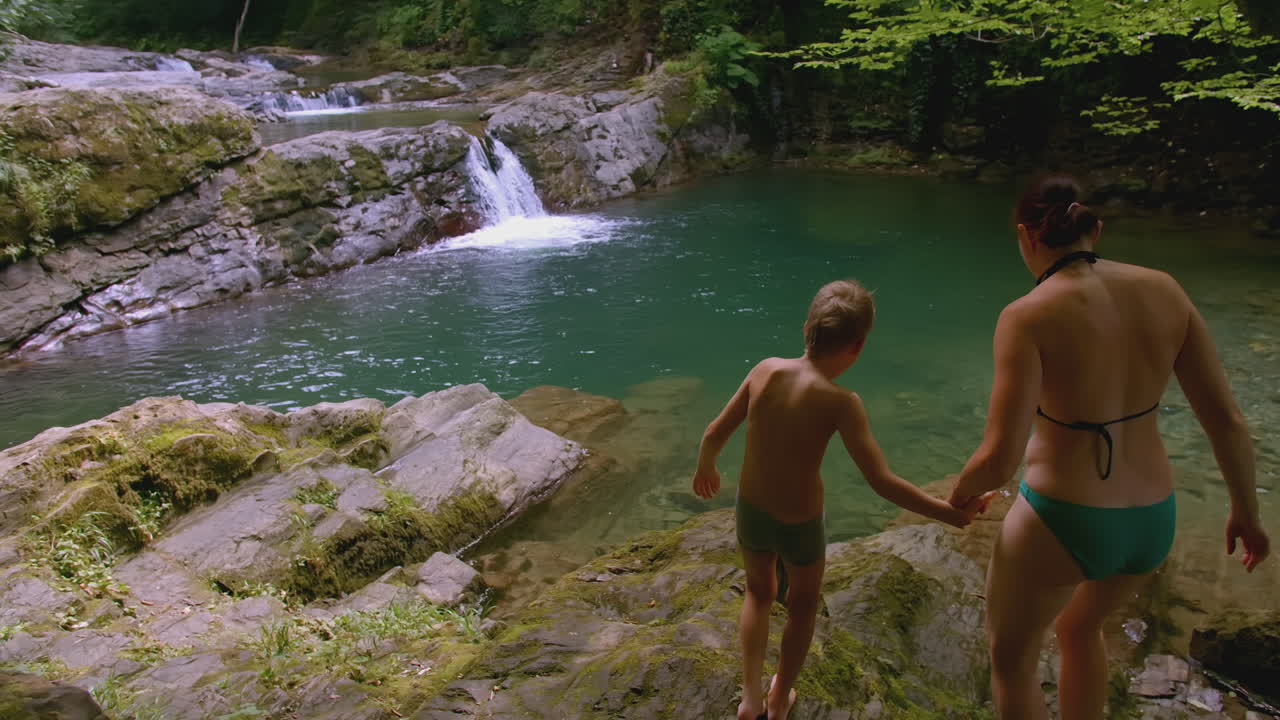 familia disfrutando de una cascada y un arroyo en un bosque