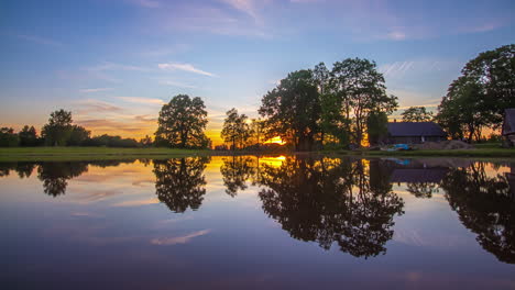 timelapse shot of beautiful sunset over wooden cottages beside a lake during evening time