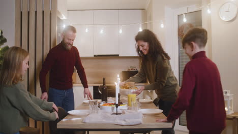 Brunette-Woman-Taking-Turkey-Out-Of-The-Oven,-Red-Haired-Man-Closes-The-Oven-And-The-Children-Come-To-The-Table-And-The-Whole-Family-Sits-For-Christmas-Family-Dinner-1