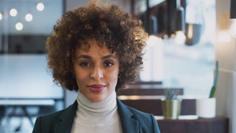 testa e spalle ritratto di una donna d'affari afroamericana sorridente che lavora in un ufficio moderno