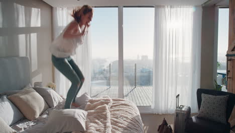 Mujer-Feliz-Saltando-En-La-Cama-En-La-Habitación-Del-Hotel-Divirtiéndose-Con-Un-Estilo-De-Vida-Exitoso-Celebrando-Disfrutando-De-Un-ático-De-Lujo