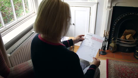 una anciana irreconocible preocupada por las deudas abriendo una carta de deuda