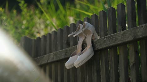 White-bridal-shoes-hanging-on-wooden-fence