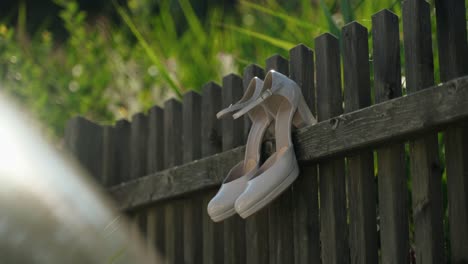white bridal shoes hanging on wooden fence
