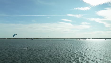 Eine-Luftaufnahme-Von-Mehreren-Kitesurfern,-Die-An-Einem-Windigen-Spätsommertag-Schnell-Auf-Dem-Wasser-Der-Donau-Segeln