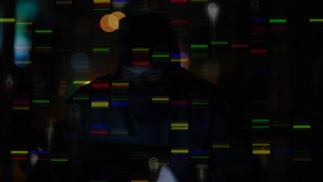 hacker wearing balaclava using computer in a dark room with colourful digital lights on the foregrou