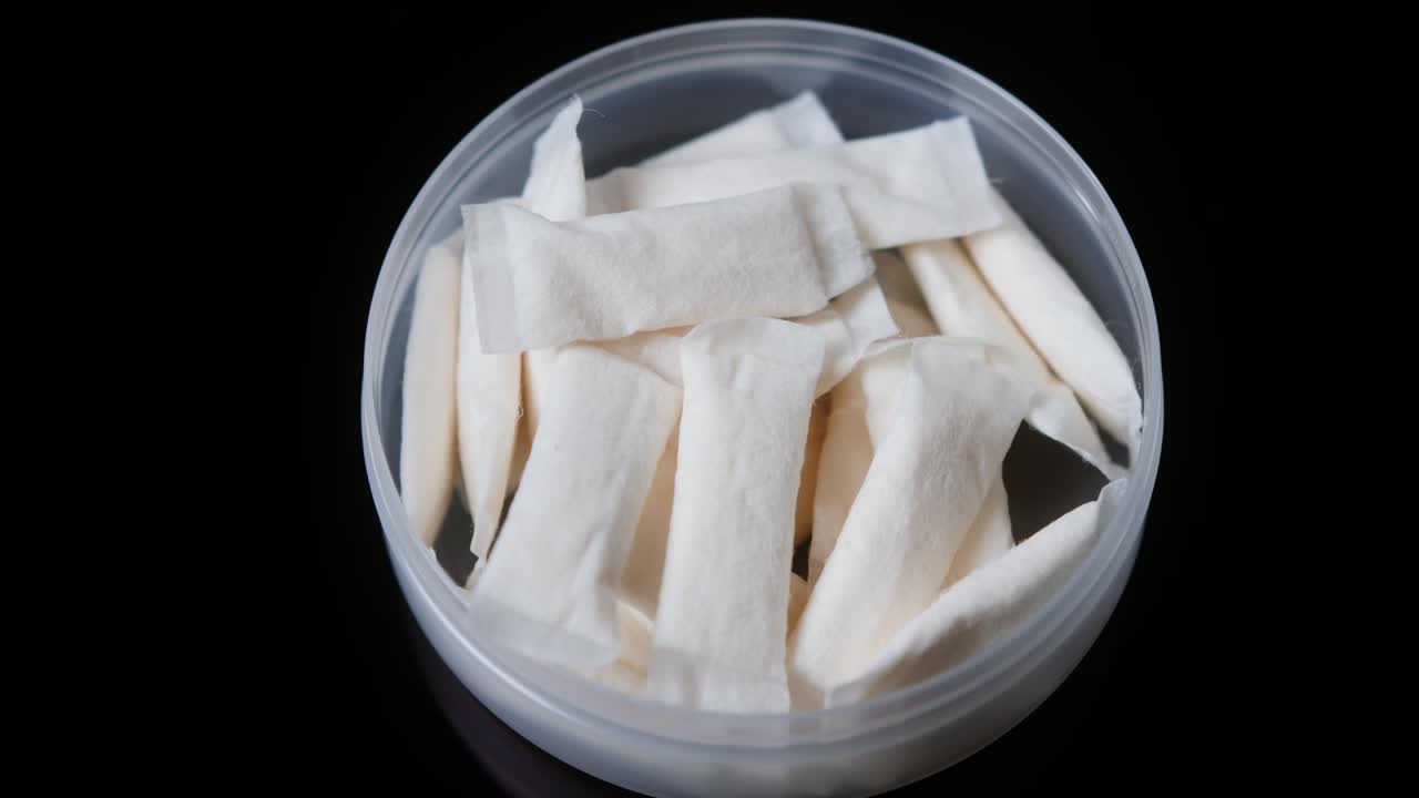 Snus nicotine tobacco close up, pack of tobacco for gum. unhealthy addiction. Man opening box with snus and taking one.