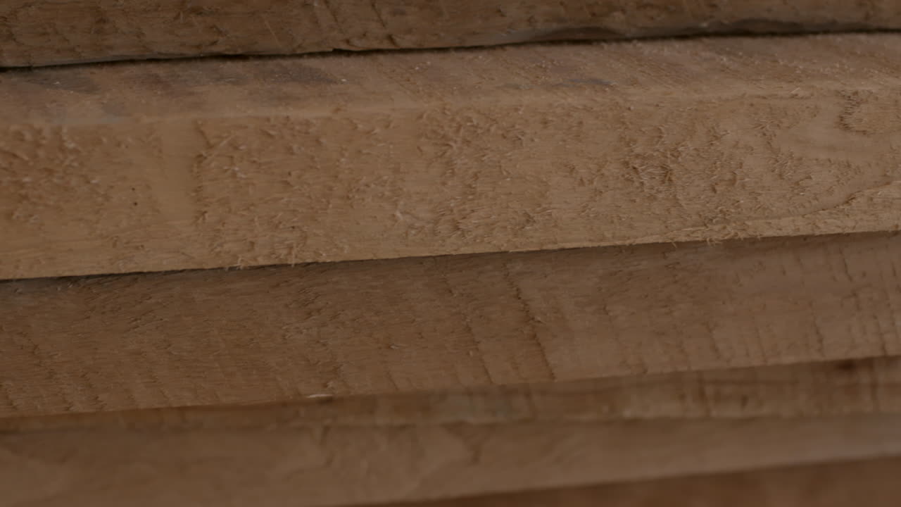 una pila de tablas de madera recién cortadas en primer plano que muestra el seguimiento de la textura a la izquierda