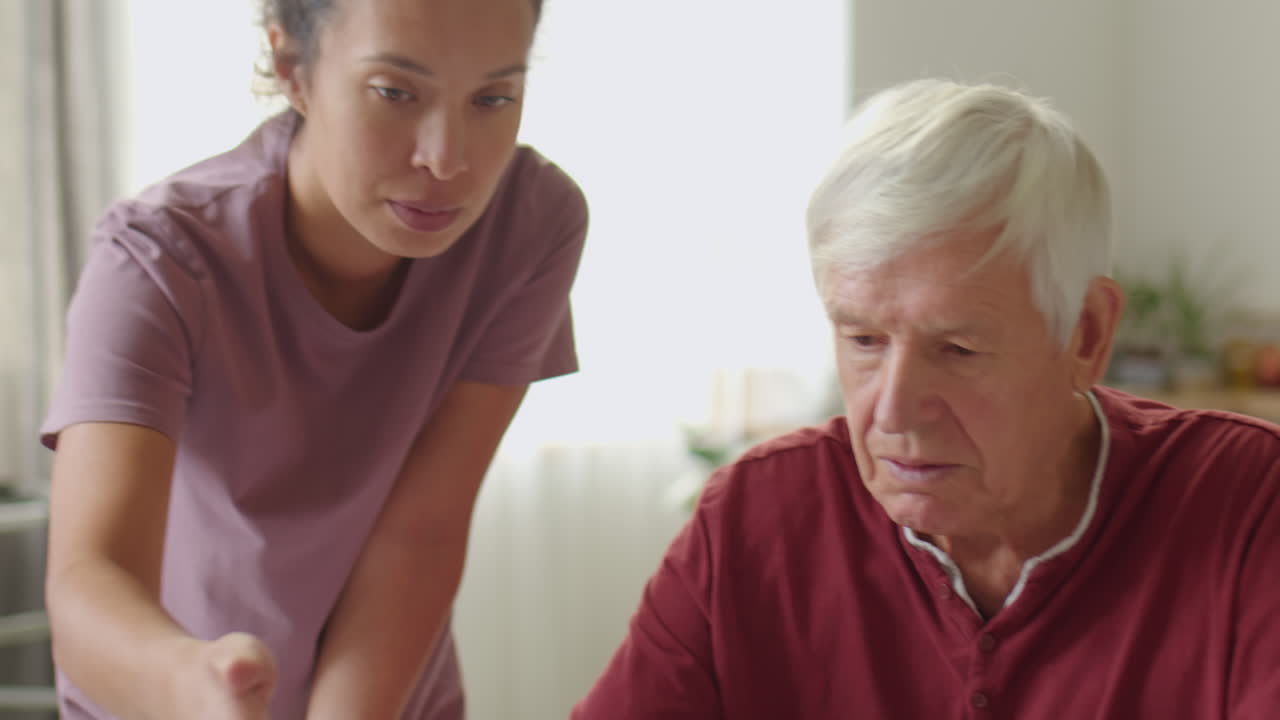 Senior Man Using the Internet with Assistance of Caregiver