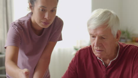 senior man using the internet with assistance of caregiver