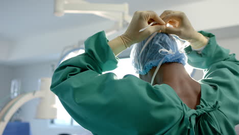 African-american-male-surgeon-tying-face-mask-in-operating-theatre,-slow-motion