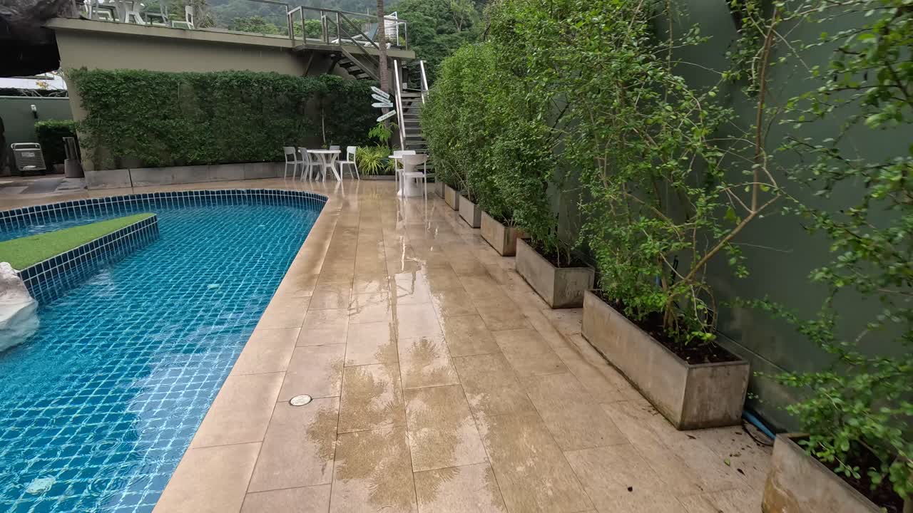 Empty pool area with rain and greenery | Premium Stock Video Footage
