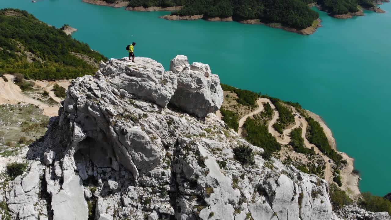 vista aérea de un viajero aventurero independiente parado en la cima de un acantilado rocoso con impresionantes vistas sobre el embalse de bovilla