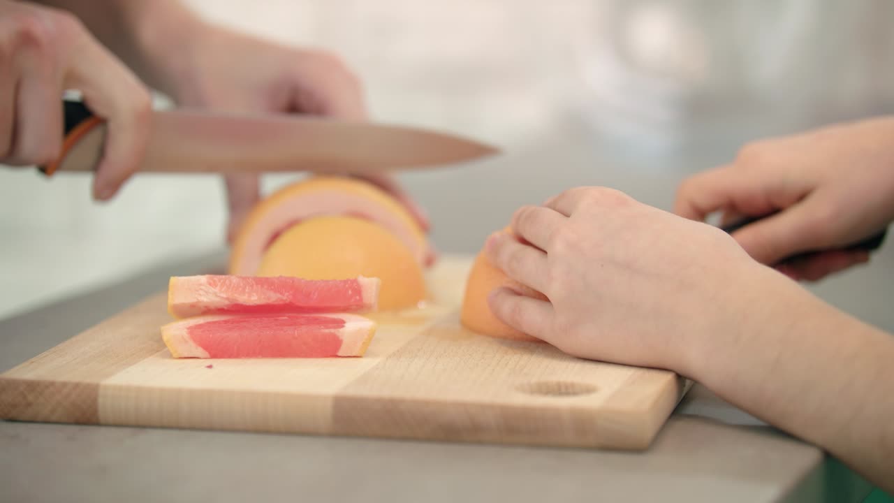 Cooking hands cutting fruit. Grapefruits sliced on wooden board