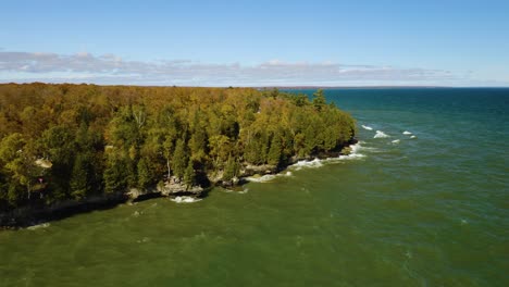 Un-Dron-Orbita-Mientras-Las-Olas-Rompen-A-Lo-Largo-De-La-Colorida-Costa-Otoñal-En-Door-County,-Wisconsin.