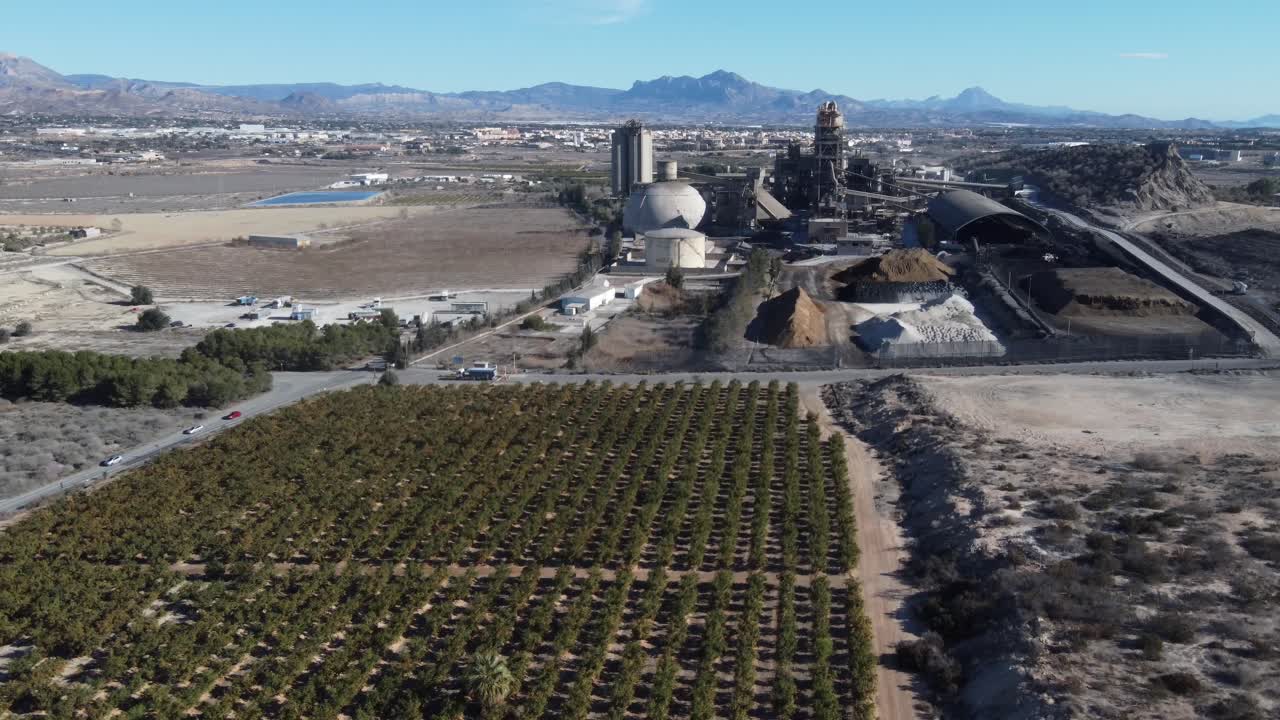 Flying away from a huge cement factory and over a citrus plantation. San Vicente del Raspeig, Spain.