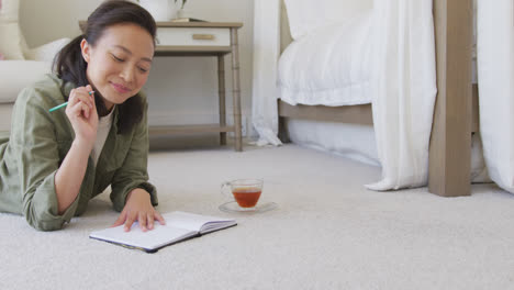 happy asian woman taking notes in bedroom, in slow motion