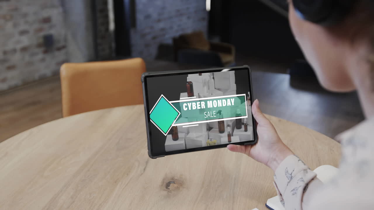 mujer biracial usando tableta en una cafetería comprando en línea en el día de venta del lunes cibernético, cámara lenta