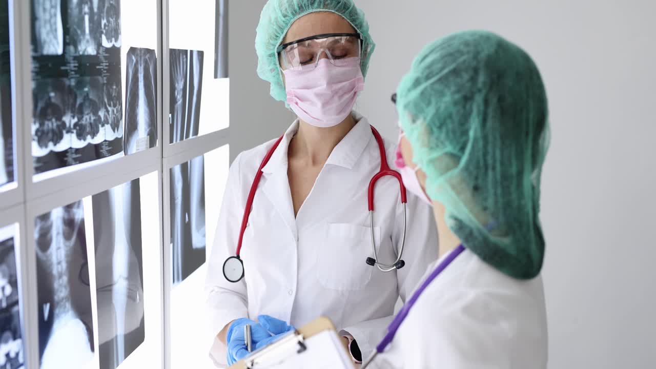 Médicos usando óculos e máscaras de proteção examinando raios-X na clínica, vídeo 4k