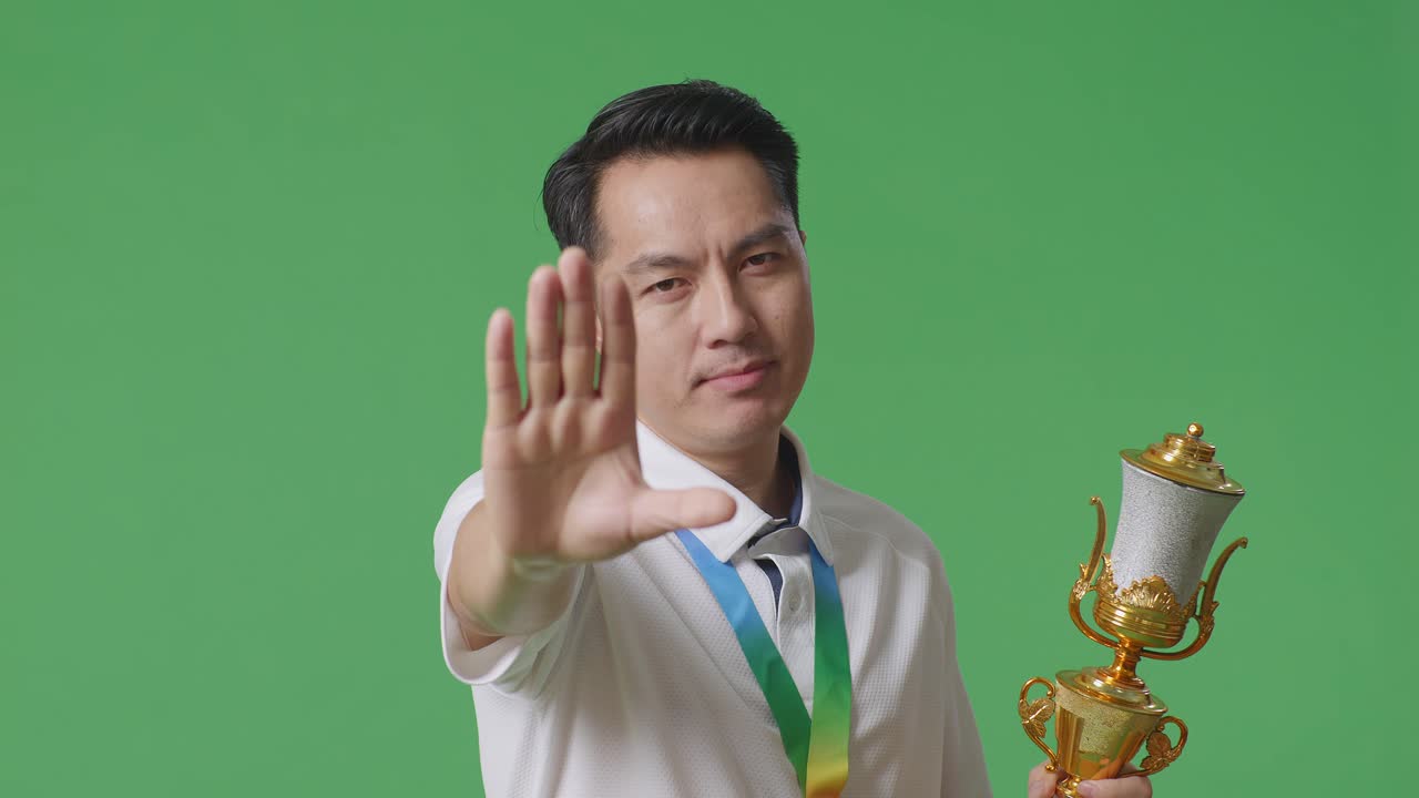 Man Holding Trophy and Making Stop Gesture