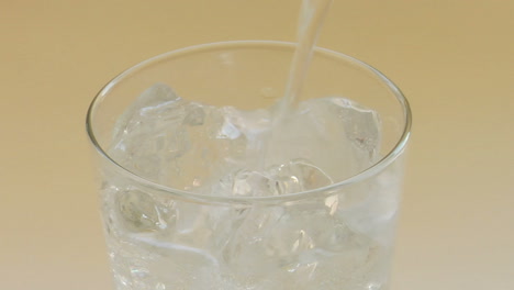 clear sparkling water poured over ice cubes in a clear glass tumbler