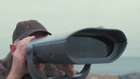 elderly man looks through binoculars sight seeing viewing at scenic landscape slow motion