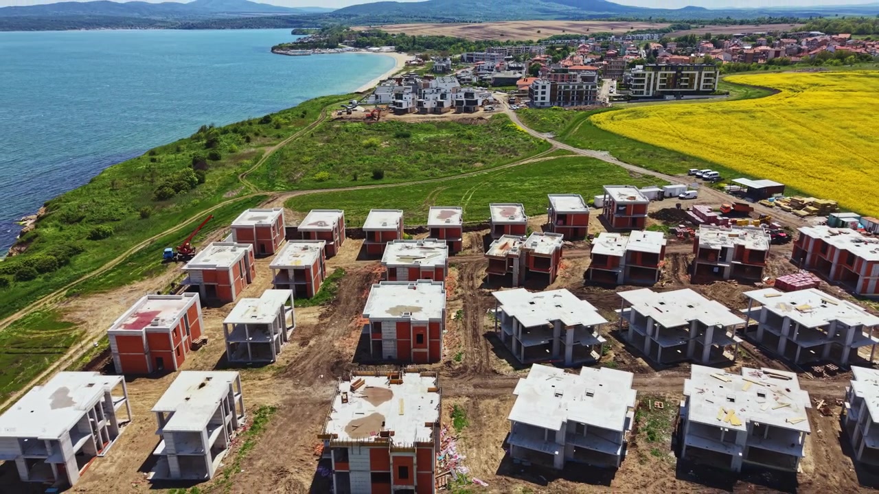 Cantiere di nuovi edifici vicino a un'area verde e a uno specchio d'acqua durante le ore diurne.