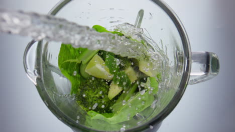 water pouring blending vegetables in blender closeup. preparing vitamin cocktail