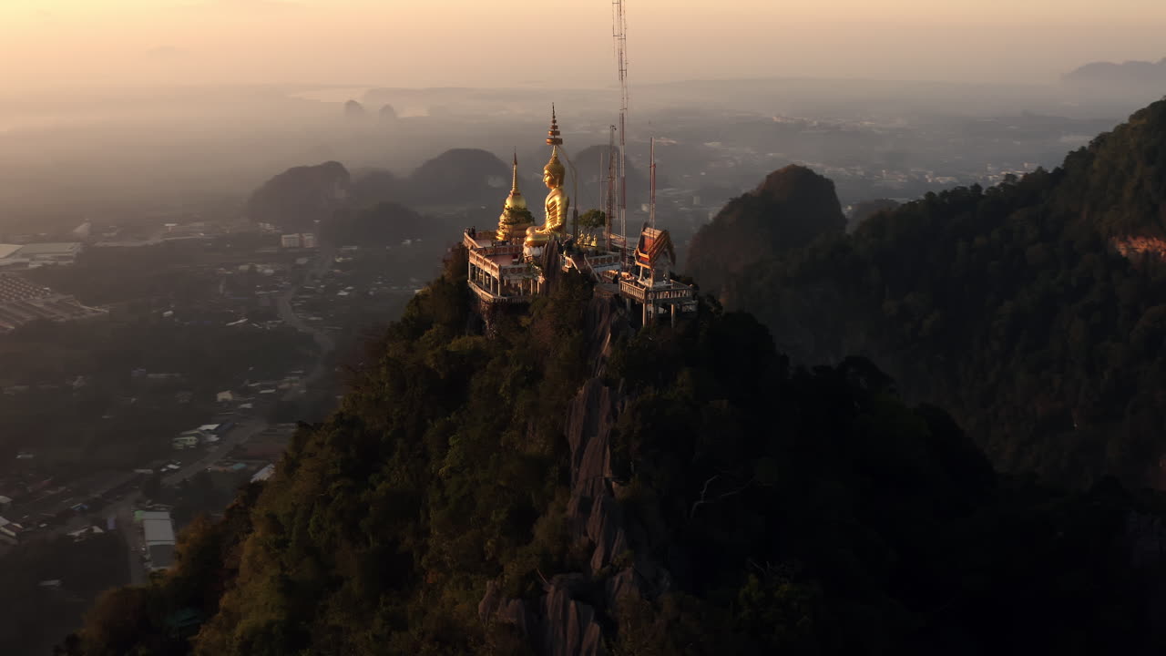 Golden Buddha Statue on Mountaintop at Sunrise