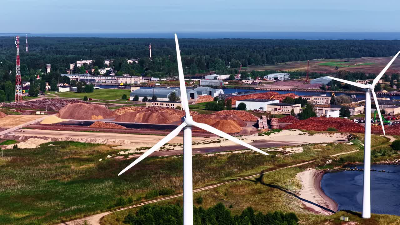 Wind turbine near coastline and industrial area captured from above in Latvia