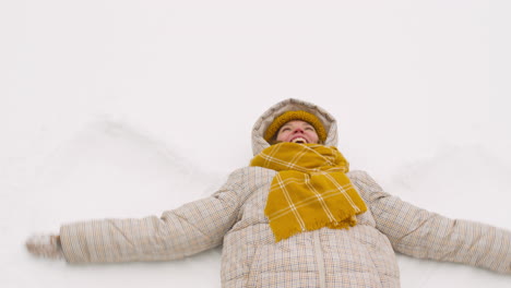 Draufsicht-Einer-Frau,-Die-Im-Winterwald-Auf-Schnee-Liegt-Und-Ihre-Arme-Bewegt