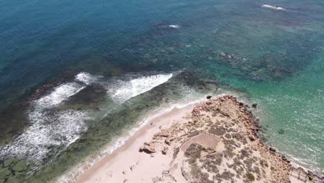 Drone-aerial-moving-backwards-showing-the-ocean-with-multiple-blue-colours-on-a-sunny-day