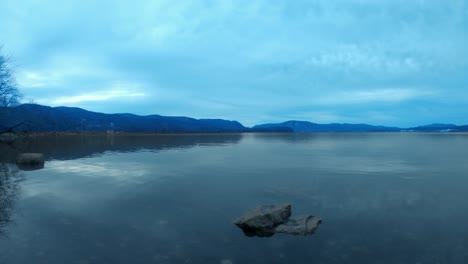 A-time-lapse-of-a-vast,-wide-river-on-a-cloudy,-dreary,-blue-day