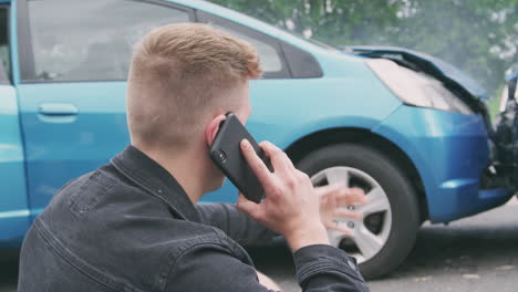 young male motorist involved in car accident calling insurance company or recovery service