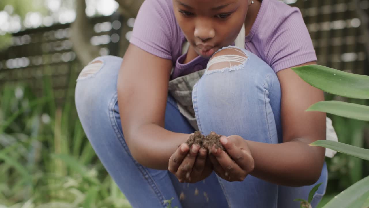 feliz chica afroamericana tocando el suelo en el jardín, cámara lenta