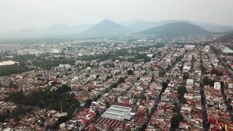 drone flight circling the industrial neighborhood in mexico city, near the basilica of guadalupe, with the guadalupe mountains in the background