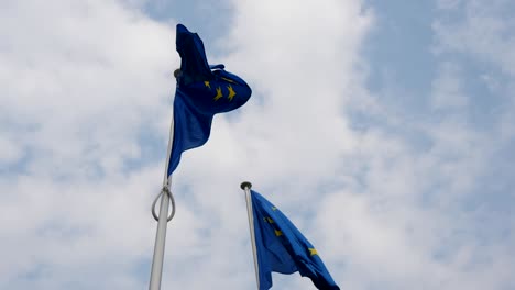 maravillosa vista de dos banderas de la unión europea ondeando en la sede de la ue en bruselas en un día soleado de primavera. el cielo es celeste y blanco.