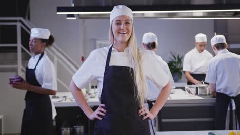 caucasian female cook working in a restaurant kitchen looking at camera and smiling